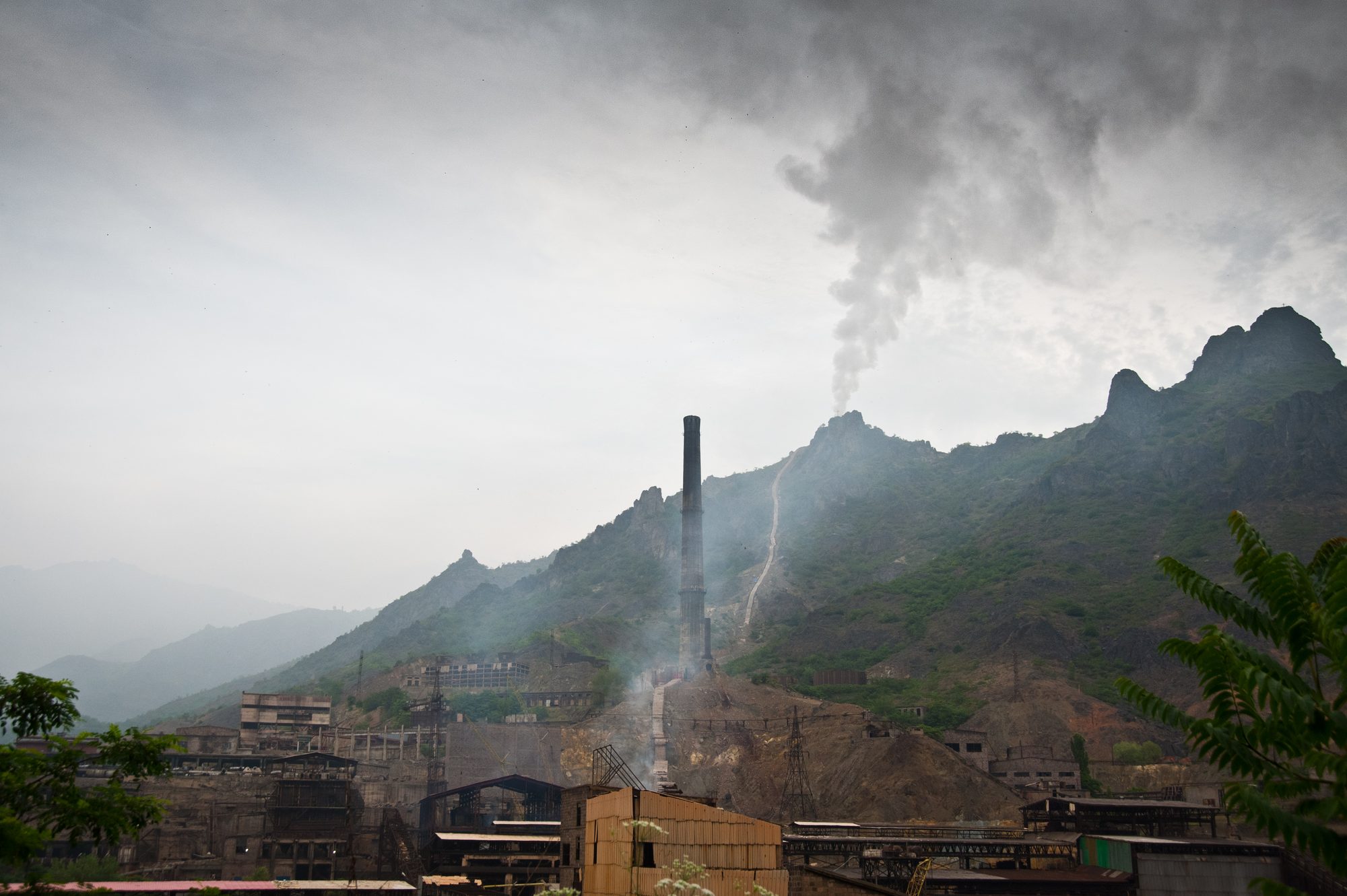 The copper smelter in Alaverdi, its chimney and a plume of smoke against green mountains