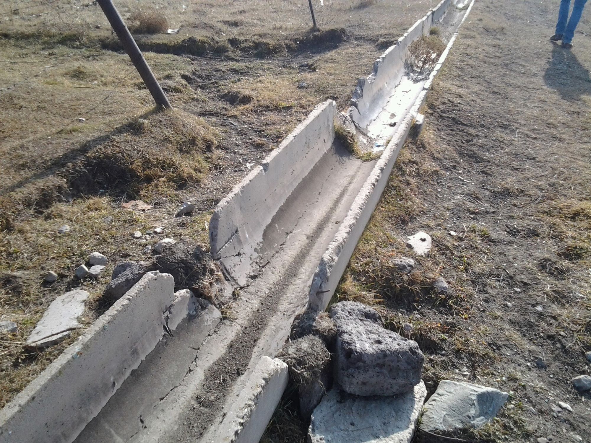 A broken concrete irrigation flume in a field